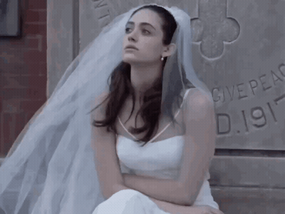 Woman In White Dress And Veil Sits By Stone Wall Saying Give Peace D.1911 GIF
