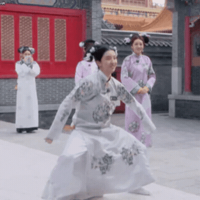 Woman In White Dress Dancing In Front Of Women In Purple Dresses GIF