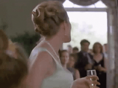 Woman In White Dress Holding Champagne Before Crowd GIF