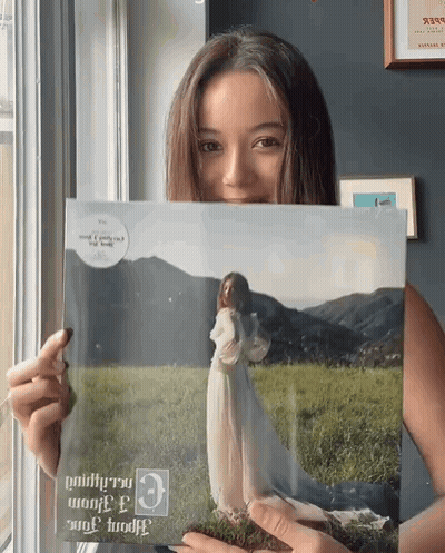 Woman In White Dress Holding Picture Of Herself GIF