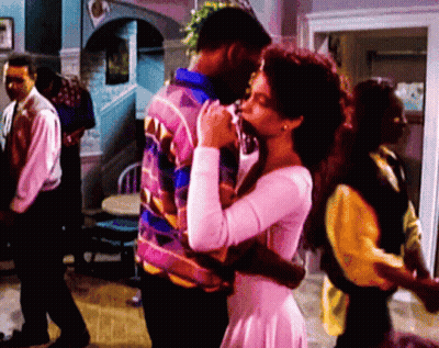 Woman In White Dress Hugging Man In Colorful Jacket GIF
