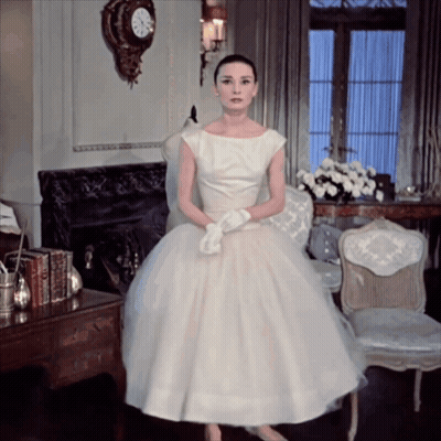 Woman In White Dress In Front Of Fireplace GIF