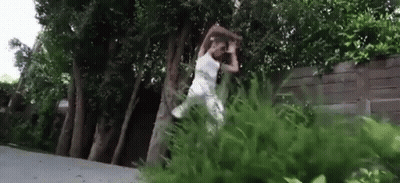Woman In White Dress Jumping Over Tree In Park GIF