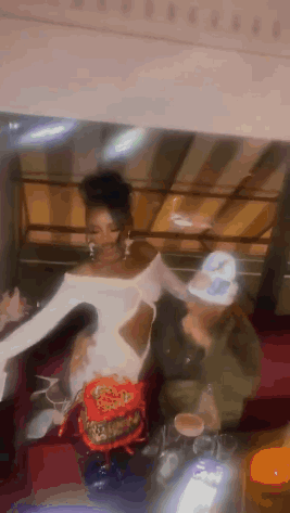 Woman In White Dress Next To Man In Green Jacket GIF