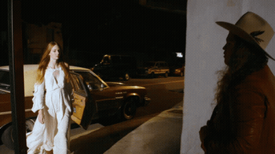 Woman In White Dress Next To Man In Hat GIF