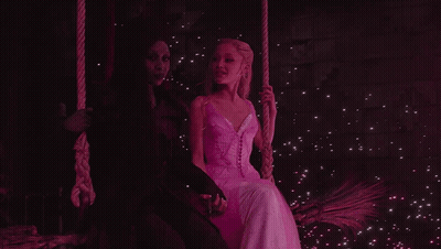 Woman In White Dress Next To Woman In Black Dress On Swing GIF