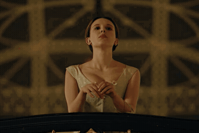 Woman In White Dress On Balcony With Hands Folded GIF
