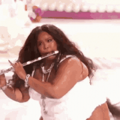 Woman In White Dress Playing Flute On Stage GIF