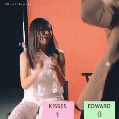 Woman In White Dress Sitting Beside Stuffed Animal And Kisses Sign GIF