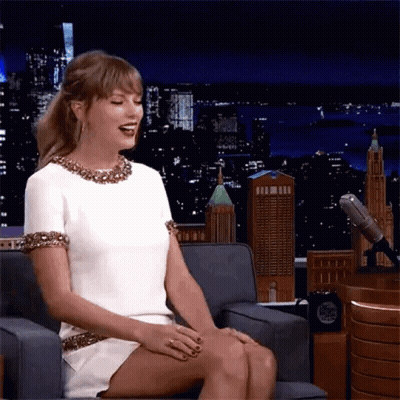Woman In White Dress Sitting Cross-Legged And Laughing GIF