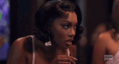 Woman In White Dress Sitting In Front Of Bravo Logo GIF