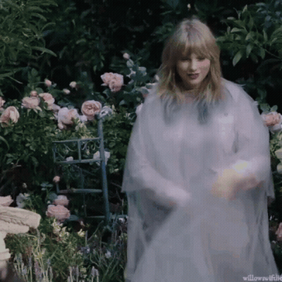 Woman In White Dress Standing In Garden With Pink Roses GIF