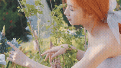 Woman in White Dress Touching Blue Flower