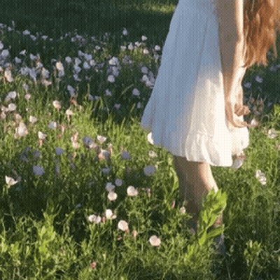 Woman In White Dress Walking Through Flower Field GIF