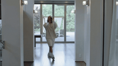Woman in White Hoodie and Shorts Walking Hallway