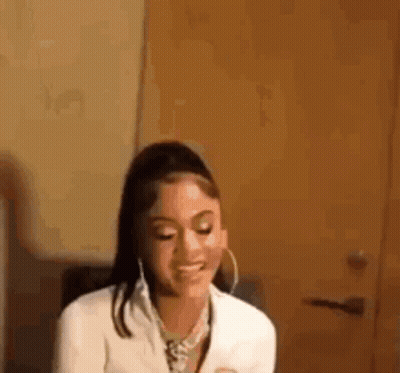 Woman In White Jacket And Hoop Earrings Smiling GIF