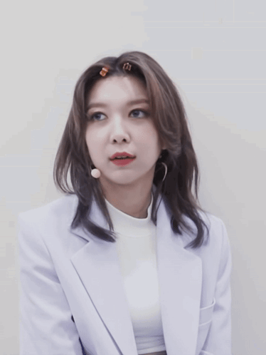 Woman In White Jacket And Turtleneck Looking At Camera GIF