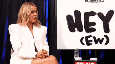 Woman In White Jacket Sitting In Front Of Hey Ew Sign GIF