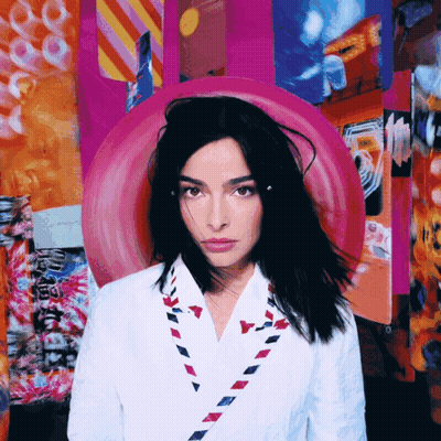 Woman In White Jacket With Red White Blue Envelope Necklace GIF