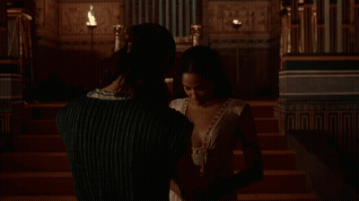 Woman In White Plunging Dress Sitting On Chair GIF