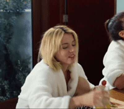 Woman In White Robe Sitting At Table With Juice GIF
