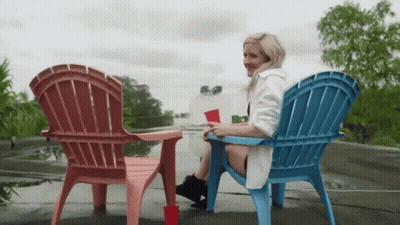 Woman In White Robe Sitting In Pink And Blue Chair GIF