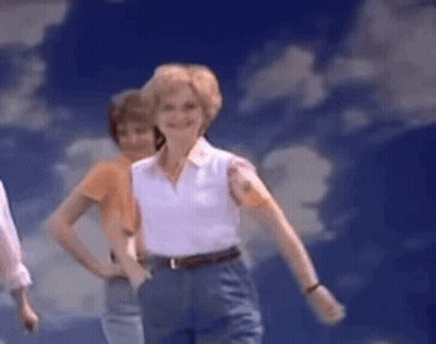 Woman In White Shirt And Blue Pants Dancing Under Blue Sky GIF