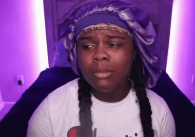 Woman In White Shirt And Purple Hat Sitting On Bed GIF