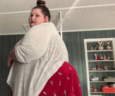 Woman In White Shirt And Red Skirt In Front Of Shelf With Vases GIF