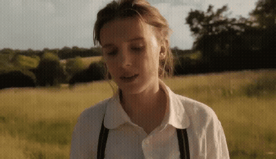 Woman In White Shirt And Suspenders In Tall Grass GIF