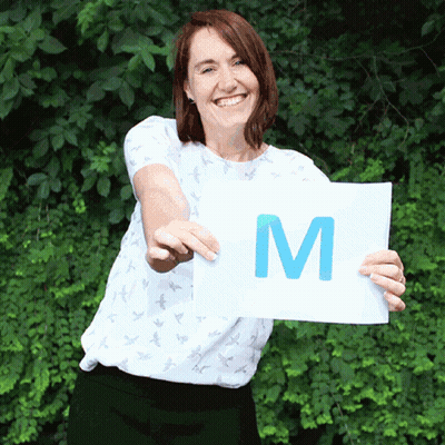 Woman In White Shirt Holding Sign That Says M GIF
