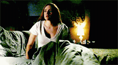 Woman In White Shirt Sitting On Bed With Lamp GIF