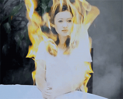 Woman In White Shirt Surrounded By Fire GIF