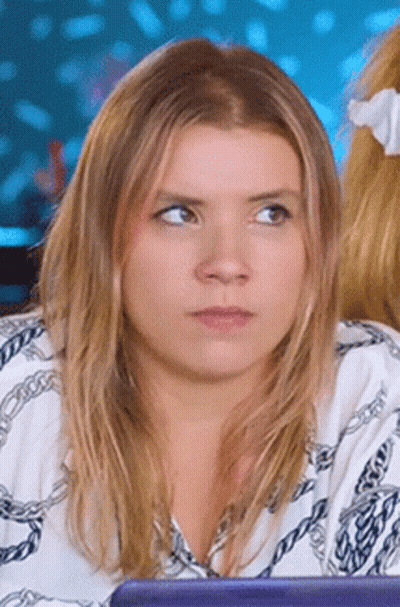 Woman In White Shirt With Chains Looking At Camera GIF