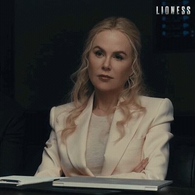 Woman In White Suit At Desk With Lioness Sign GIF