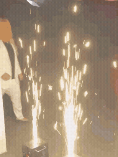 Woman In White Suit Next To Fireworks GIF