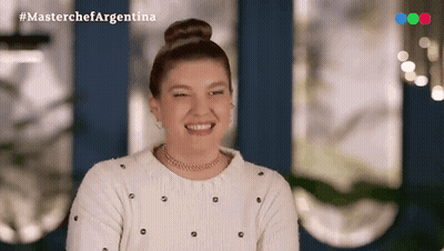 Woman In White Sweater And Bun Smiling With MasterChef Argentina Logo GIF