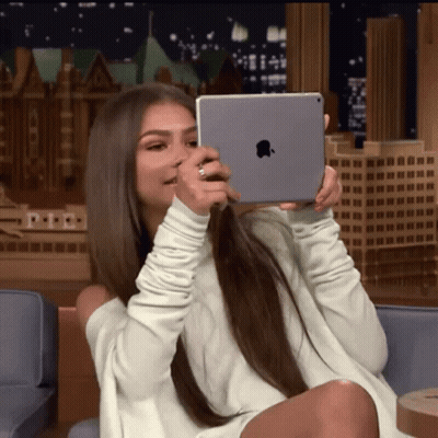 Woman In White Sweater Holding IPad GIF