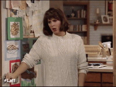 Woman In White Sweater In Front Of Door With Laff GIF