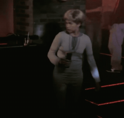 Woman In White Sweater Standing In Dark Room GIF
