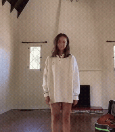 Woman In White Sweater Standing In Living Room GIF