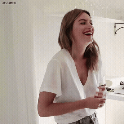 Woman In White T-Shirt And Jeans Smiling Holding Glass GIF
