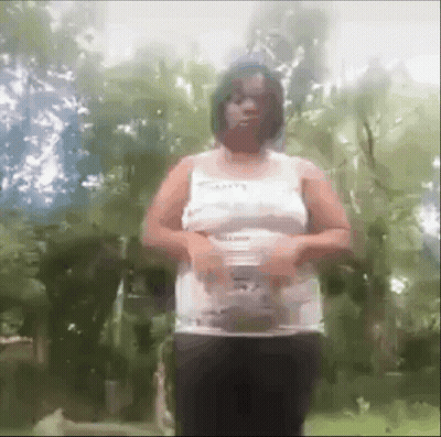 Woman In White Tank Top And Black Pants Standing In Forest GIF