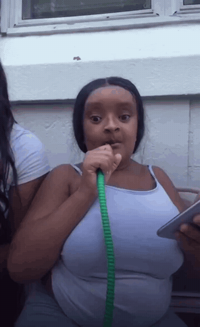 Woman In White Tank Top Drinking From Green Hose GIF