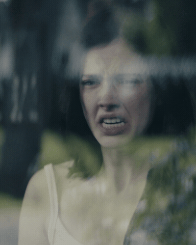 Woman In White Tank Top Making Funny Face At Window GIF