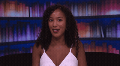 Woman In White Tank Top Smiling At Bookshelf GIF