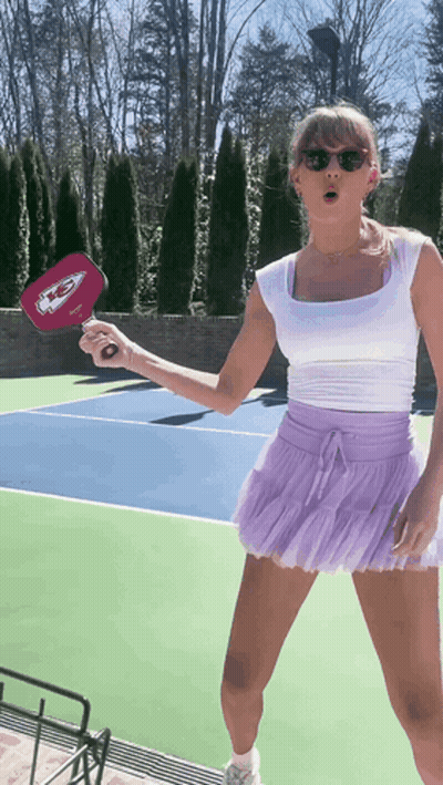 Woman In White Top And Purple Skirt Holding Chiefs Paddle GIF