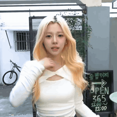 Woman In White Top In Front Of Open 365 Sign GIF