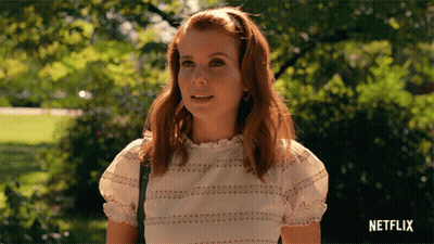 Woman In White Top Standing In Park With Netflix Logo GIF