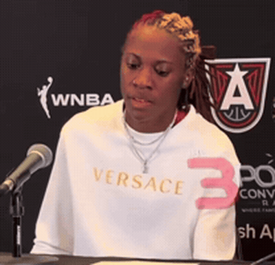 Woman In White Versace Shirt At Podium GIF
